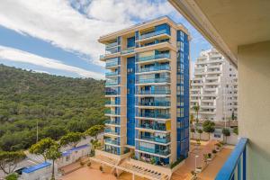 apartamentowiec z niebieskimi balkonami i drzewami w obiekcie Beach and Green w Alicante