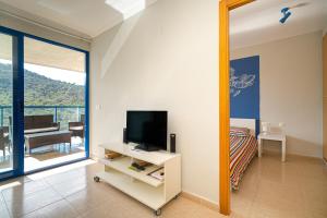 een kamer met een tv en een slaapkamer met een balkon bij Beach and Green in Alicante