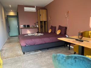 a bedroom with a large bed and a table and a tableablish at Natuur lodge in Blesdijke