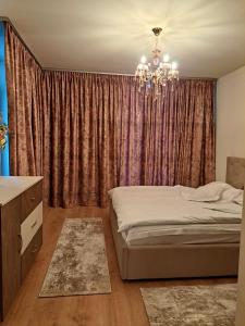 a bedroom with a bed and a chandelier at Monica City Apartament in Timişoara