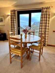 a dining room table and chairs with a large window at Myrtle Cottage in Lairg