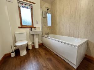 a bathroom with a tub and a toilet and a sink at Myrtle Cottage in Lairg