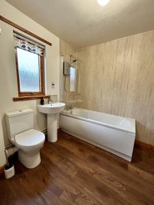 a bathroom with a tub and a toilet and a sink at Myrtle Cottage in Lairg