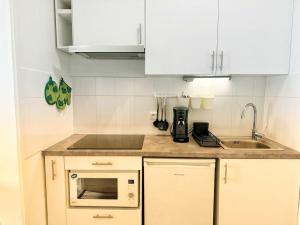 a small kitchen with a sink and a microwave at Charme, balcon, parking, piscine, tramway, Netflix in Mérignac