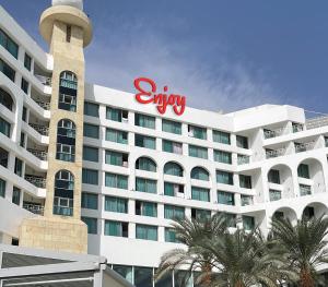 a large hotel with a sign on the side of it at Enjoy Dead Sea Hotel -Formerly Daniel in Ein Bokek