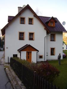 a man standing in front of a white house at Privát Fedoriška in Špindlerův Mlýn