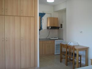 阿馬利亞波利的住宿－安格娜提公寓，厨房配有木制橱柜和桌椅