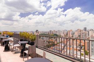 a balcony with tables and chairs and a city skyline at Vossa Bossa Allianz in Sao Paulo