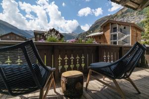 deux chaises sur une terrasse avec des montagnes en arrière-plan dans l'établissement Village Apartment with Matterhorn View, à Zermatt