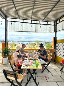 un grupo de personas sentadas en una mesa comiendo comida en Như Mây Homestay en Phu Quoc