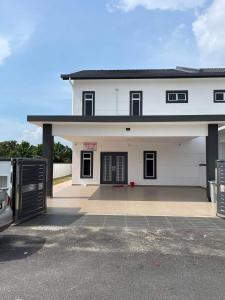 una casa blanca con un coche aparcado delante de ella en cuti-cuti port dickson homestay en Port Dickson
