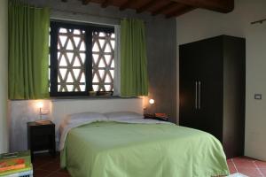een slaapkamer met een bed en een raam met groene gordijnen bij Il Poggiolo Delle Rose Bed&Breakfast in Tavarnuzze