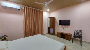 een slaapkamer met een bed, een tv en een stoel bij Soham Beach Resort, Diveagar in Diveagar