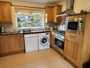 a kitchen with a washer and dryer and a window at Fern Cottage in Lairg