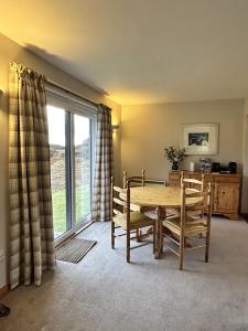 a dining room with a table and chairs and a window at Fern Cottage in Lairg