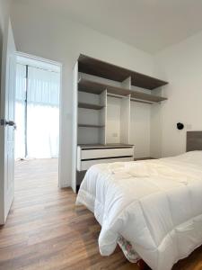 a white bedroom with a bed and a desk at Complejo Duendes del Maiten in San Carlos de Bariloche