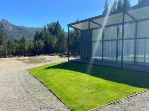 una casa con un prato verde davanti di Complejo Duendes del Maiten a San Carlos de Bariloche