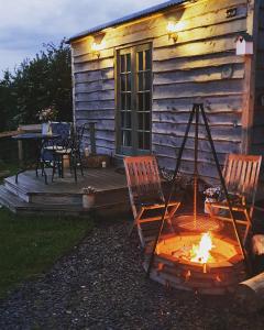 a fire pit in front of a log cabin at Hut Haf in Talacre