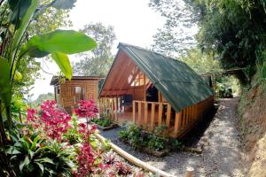 a small wooden cabin in a garden with flowers at Finca Colibrí Zafiro, Altos del Rosario in Cali