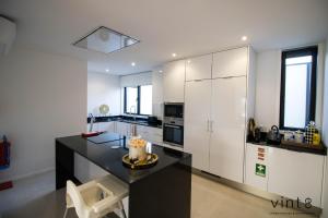 a kitchen with a black counter and white cabinets at Casa do Golfe by VinteOito in Amarante