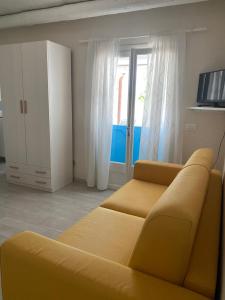 a living room with a yellow couch and a window at Casa vacanza il "Vignale" in Portopalo