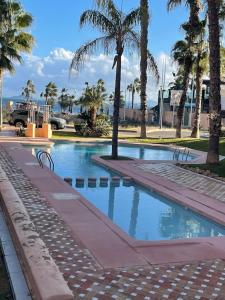 una piscina con palmeras en un parque en Casa Estrellita - Lovely beachside 3 bedroom duplex flat, en Los Alcázares