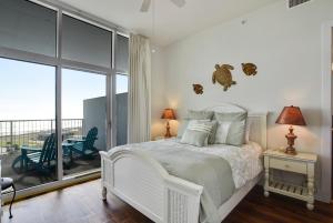 a white bedroom with a bed and a balcony at Emerald 1111 in Galveston