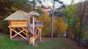 una casa en el árbol con escalera y techo de hierba en Pine Point en Trenčianske Teplice