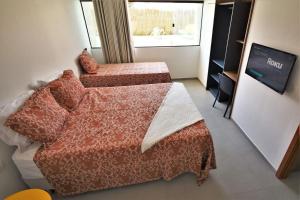a bedroom with two beds and a tv and a window at Condôminio Velas do Porto in Porto De Galinhas