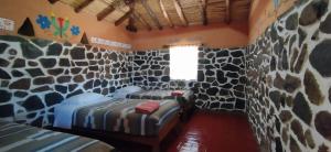 a room with two beds in a rock wall at Lodge Mirador San Antonio- Colca in Coporaque