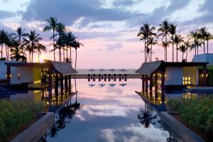 ein Resortpool mit Palmen und dem Meer im Hintergrund in der Unterkunft JW Marriott Khao Lak Resort and Spa in Khao Lak