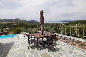 a table and chairs with an umbrella on a patio at Villa Rokanes Glass Stone with Pool in Kouvéllai