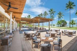 un patio al aire libre con mesas, sillas y palmeras en JW Marriott Khao Lak Resort and Spa en Khao Lak
