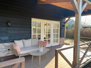 a patio with a couch and a table on a deck at B&B De Porrel in Polsbroek