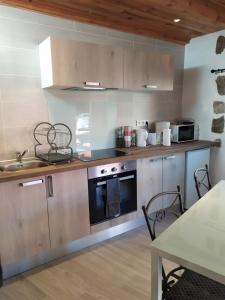 uma cozinha com um fogão, um lavatório e uma mesa em La maison D'Orée em Polignac