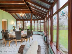 un giardino d'inverno con tavolo, sedie e finestre di Vicarsford Farmhouse with Hot Tub a Leuchars