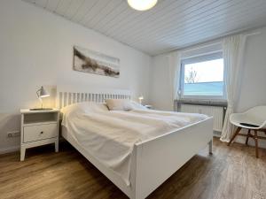 a white bedroom with a white bed and a window at Gästehaus am Kampland - Wohnung 4 in Dahme