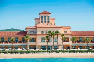 ein großes Gebäude mit Palmen davor in der Unterkunft Le Meridien Ra Beach Hotel and Spa in El Vendrell