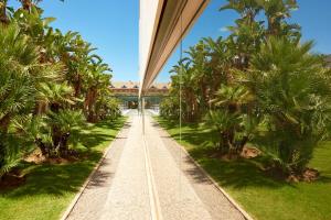 einen Gehweg mit Palmen und einer Brücke in der Unterkunft Le Meridien Ra Beach Hotel and Spa in El Vendrell