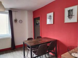 een eetkamer met een rode muur met een tafel en stoelen bij Charmant appartement au calme avec parking in Besançon