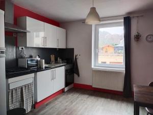 a kitchen with white cabinets and a large window at Charmant appartement au calme avec parking in Besançon