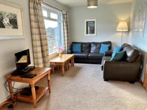 a living room with a couch and a table at Orchid Cottage in Lairg