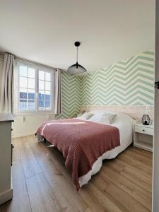 sypialnia z łóżkiem i ścianą w paski w obiekcie Bel appartement plein centre 100m de la mer w mieście Merville-Franceville-Plage