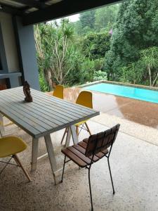 een houten tafel en stoelen met een tafel en een zwembad bij BAA BAA RESIDENCE in Hillcrest