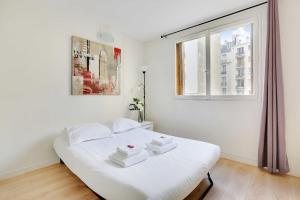 a white bed in a white room with a window at Cozy apartment - Paris Porte de Versailles in Paris