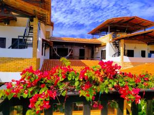un balcone con fiori rossi di fronte a un edificio di Pousada Sahara a Jericoacoara