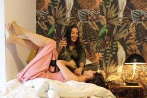 dos mujeres sentadas en una cama con sus piernas en el aire en Hotel Marcos Gamero, en Talca
