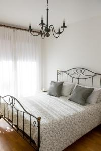 Dormitorio blanco con cama grande y lámpara de araña en Pelèr13, en Riva del Garda