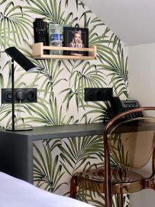 a bedroom with a green and white leafy wall at Logis Hotel du Maine in Laval