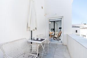 Habitación blanca con sillas blancas y mesa en El Erizo Apartamentos, en Tarifa